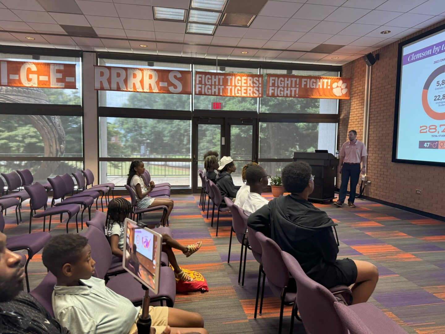 A speaker addresses an audience in a lecture hall with banners overhead.