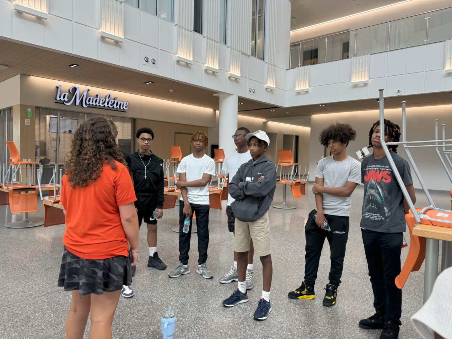 A group of young people standing in a spacious modern indoor area.