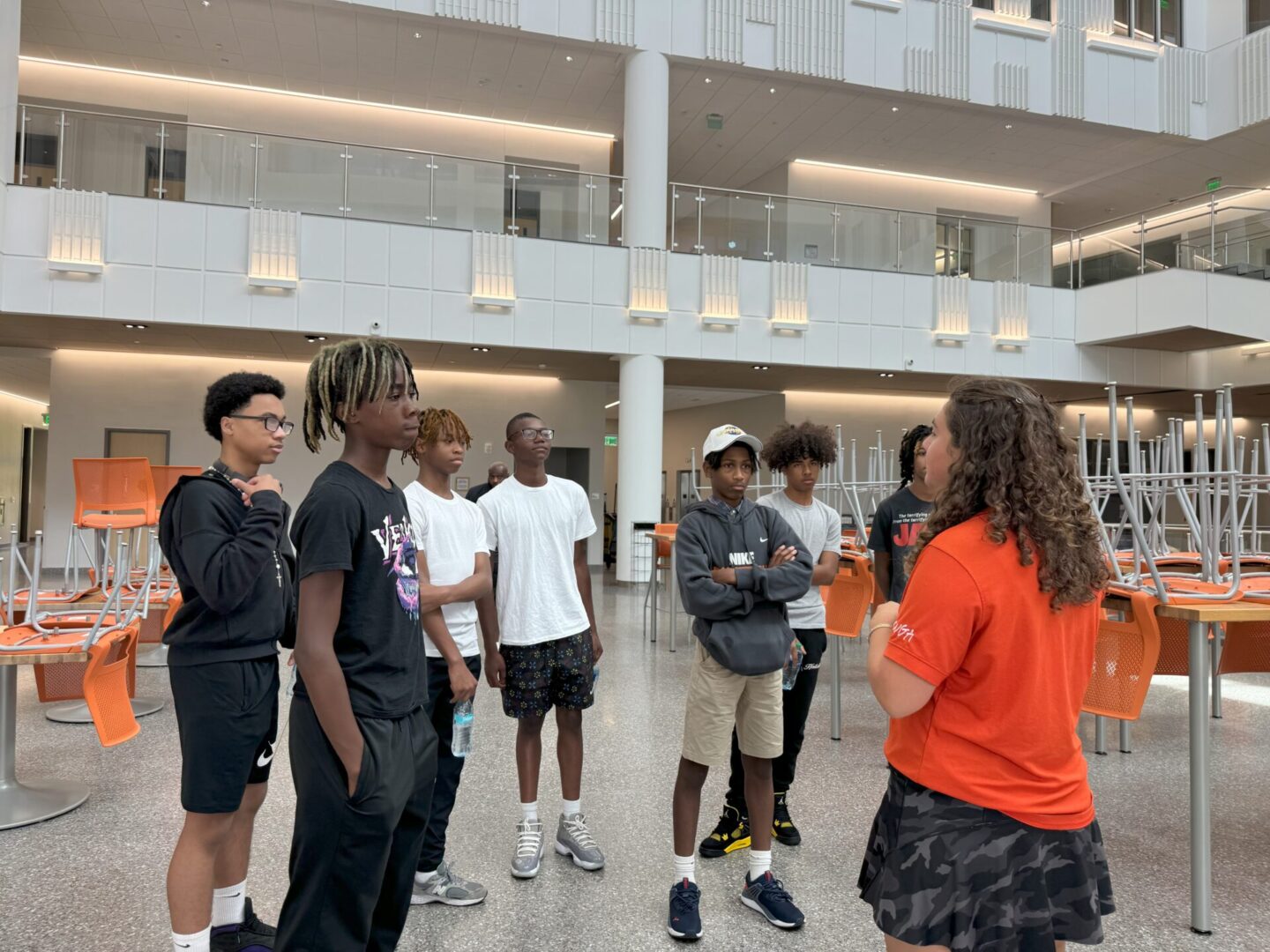 A group of young people listening to a guide in a modern indoor space.