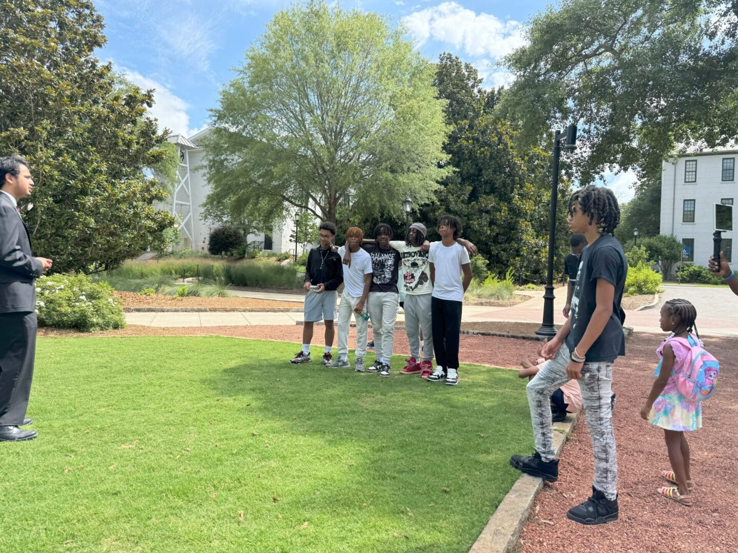 Group of young people standing and chatting in a park on a sunny day.