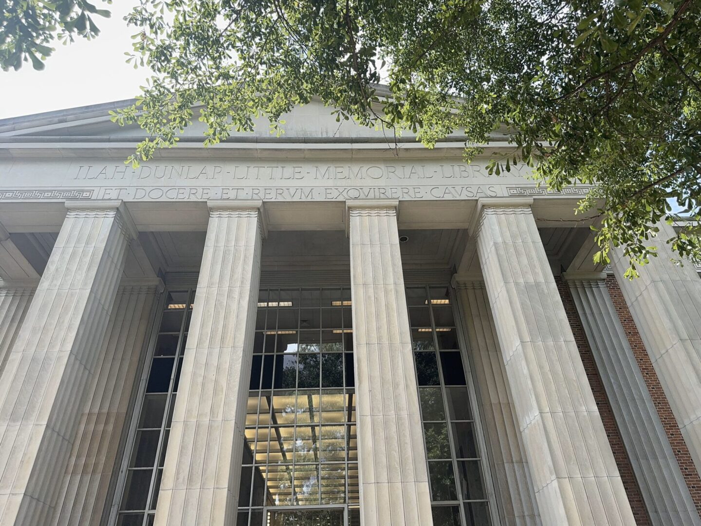 Front view of a classical building with tall columns and a tree overhead.